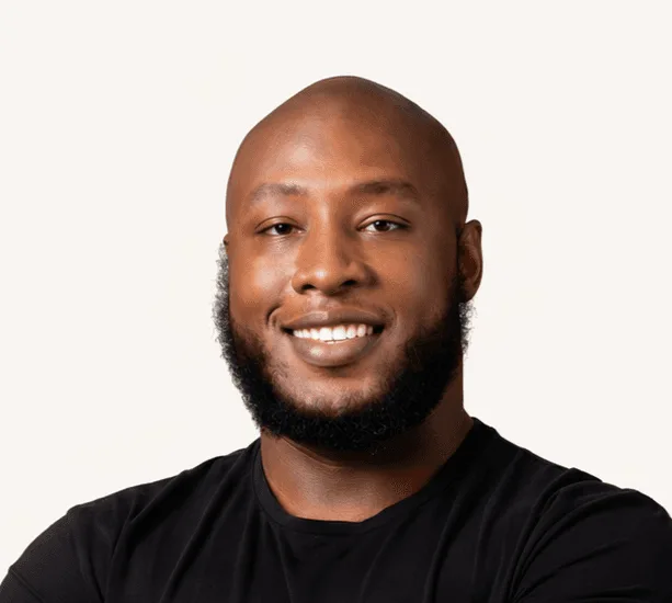 Portrait of Amadeus Rennalls smiling, wearing a black T-shirt against a pale background